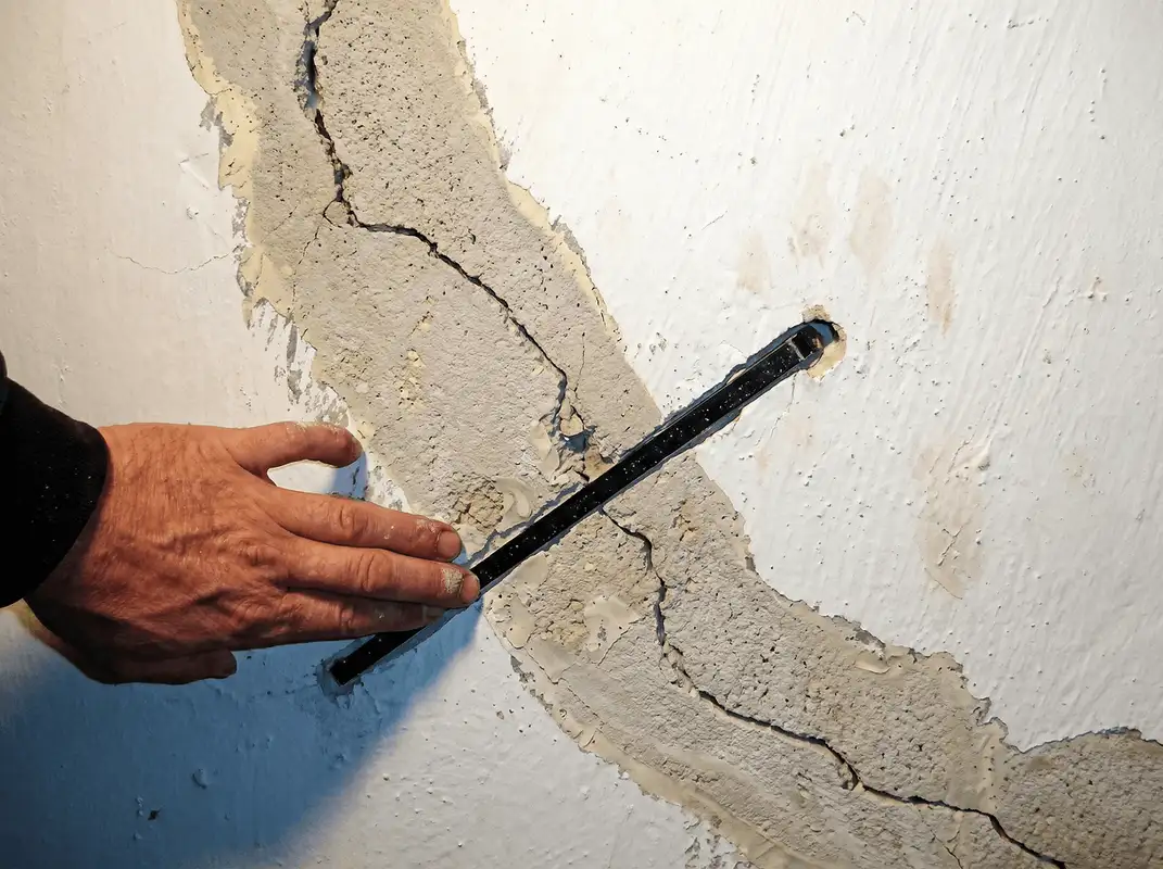 A wall with a large crack is being inspected by a professional in Yonkers, NY
