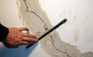 A wall with a large crack is being inspected by a professional in Yonkers, NY